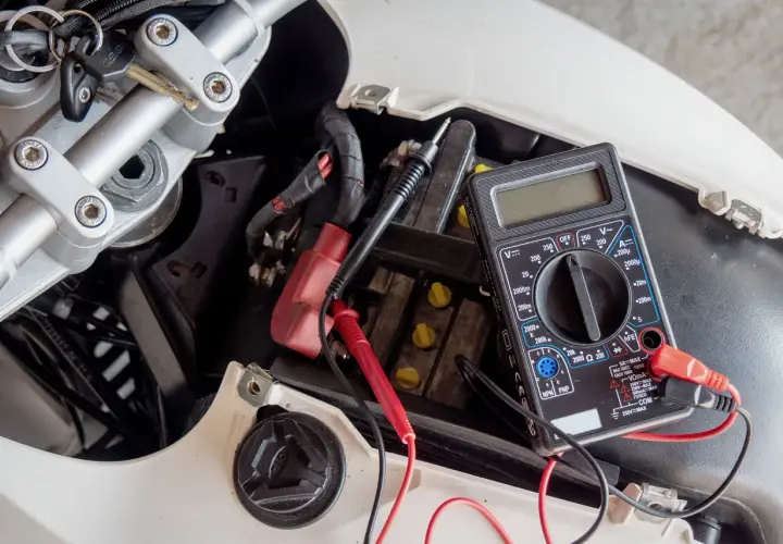 Controllo batteria scooter con multimetro. Si sta per caricare la batteria dello scooter in casa, verificando la tensione con un tester.