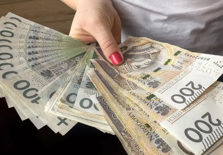 Dłoń trzyma wachlarz polskich banknotów 100 i 200 zł. To spory pensum gotówki, które można przeznaczyć na różne wydatki.