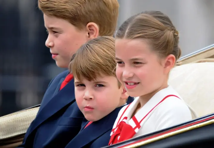 Księżniczka Charlotte uśmiecha się, siedząc w karocy obok swoich braci.