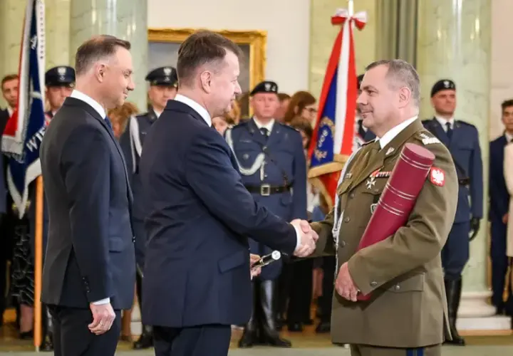 Uroczystość wręczenia nominacji generalskich. W centrum korpus generałów, prezydent Duda wręcza dokument.