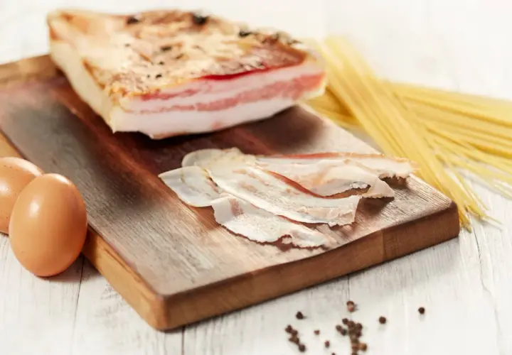 Ingredienti per una pasta con guanciale perfetta: un pezzo di guanciale, uova e spaghetti.