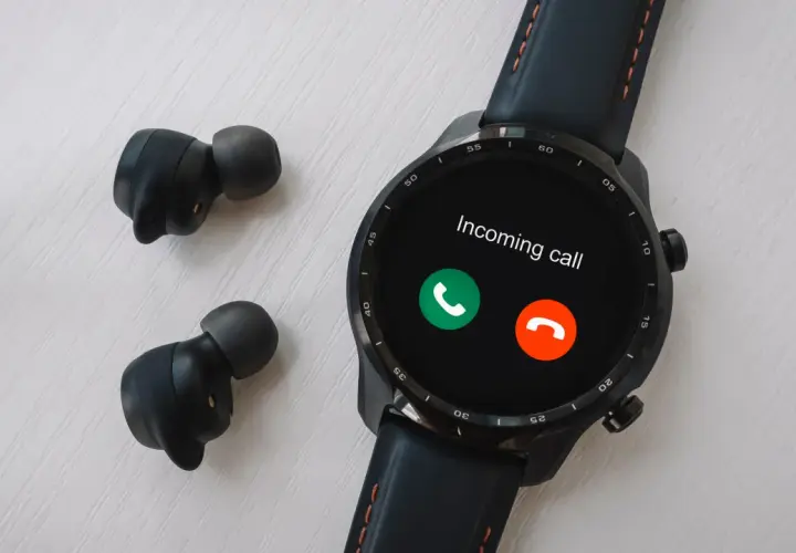 Czarny smartwatch z ekranem pokazującym połączenie przychodzące i bezprzewodowe słuchawki.
