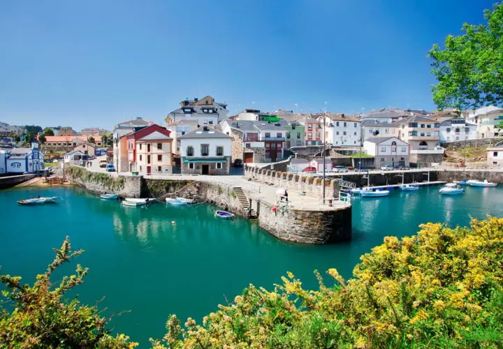 El pintoresco puerto vega, con sus casas coloridas y barcos meciéndose en aguas turquesas, bajo un cielo azul.