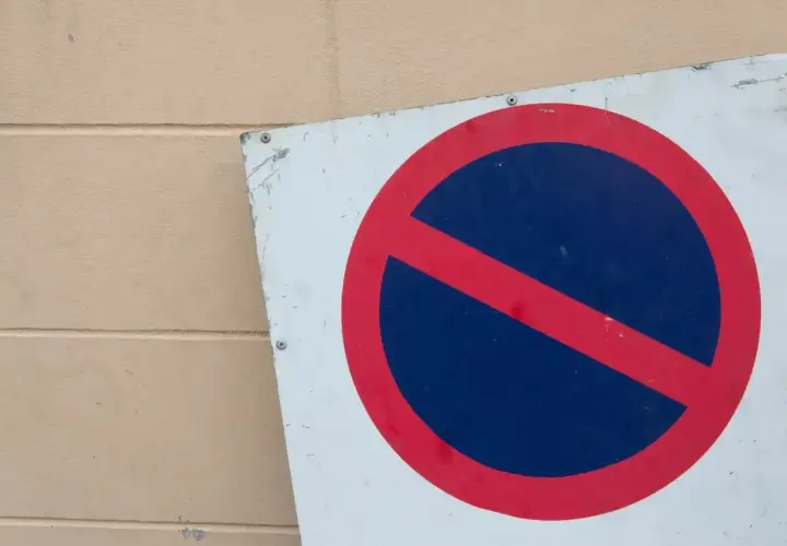 Znak b35 zakazu zatrzymywania się. Czerwone koło z czerwoną przekątną na niebieskim tle.