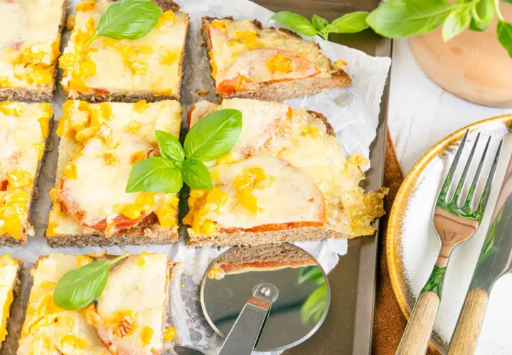 Herzhafte hackfleischpizza vom blech, Landfrauen-Art, mit Tomaten und Käse überbacken, garniert mit frischem Basilikum.