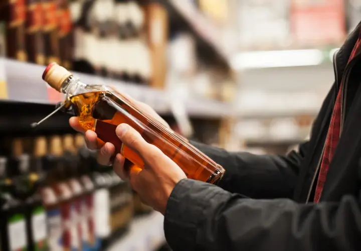 Ręce trzymają butelkę whisky, zastanawiając się, ile alkoholu można przewieźć samolotem z USA do Polski.