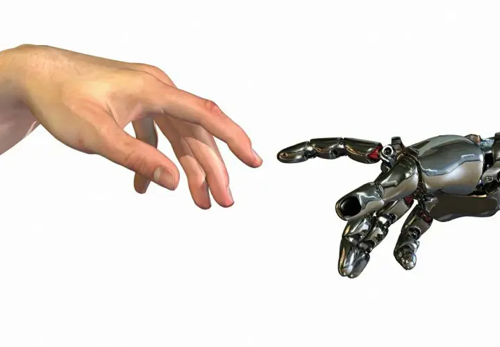 Ludzka dłoń i mechaniczna ręka zbliżają się do siebie, niemal dotykając. To symboliczny touche między człowiekiem a technologią.