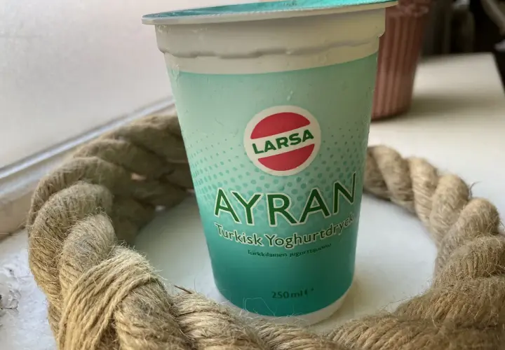 En kopp Larsa Ayran, turkisk yoghurt, står på ett bord. Perfekt för ett snabbt ayran recept.
