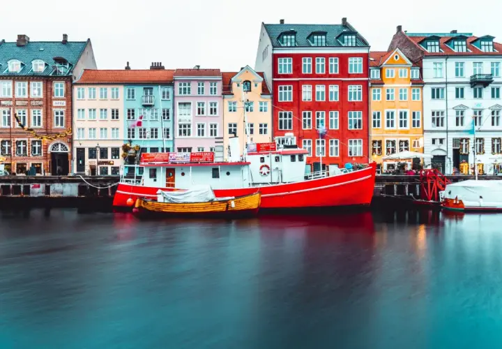 Bateaux rouges et jaunes amarrés devant des maisons colorées, typiques de Copenhague.