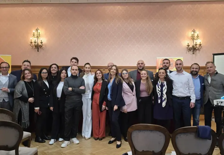 Gruppo di persone posa davanti a uno striscione della Fondazione Archimede.