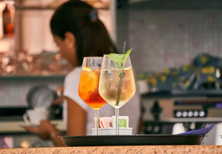 Dwa drinki: pomarańczowy Aperol Spritz i jasny Hugo. Różnica między aperol spritz a hugo w składnikach i kaloryczności jest widoczna.
