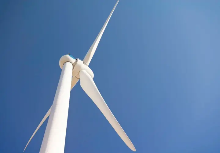 Biała turbina wiatrowa bez pozwolenia na tle błękitnego nieba.