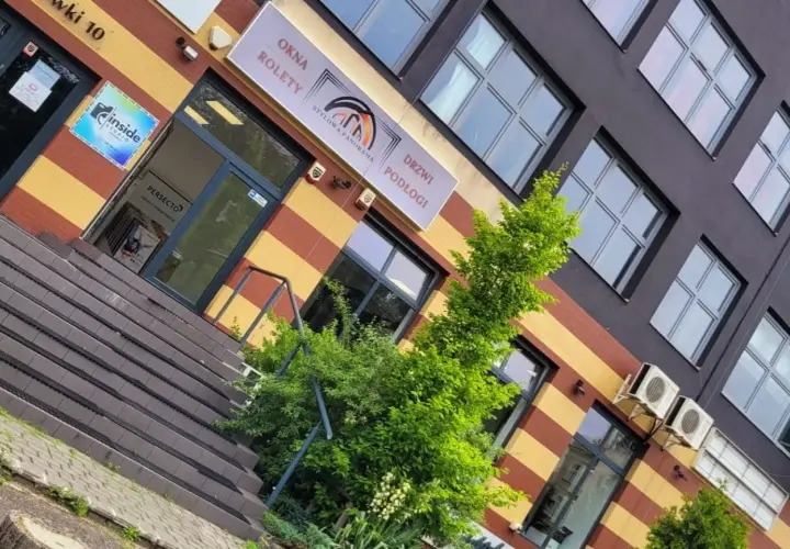 Elegancki budynek z oknami i drzwiami, z zielenią przed wejściem.