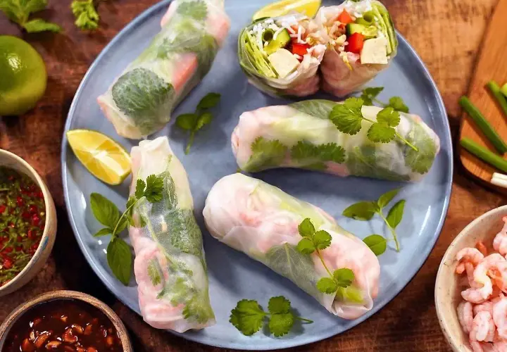 Färska sommarrullar med räkor och grönsaker, serverade med en smakrik vietnamesisk sås och limeklyftor.