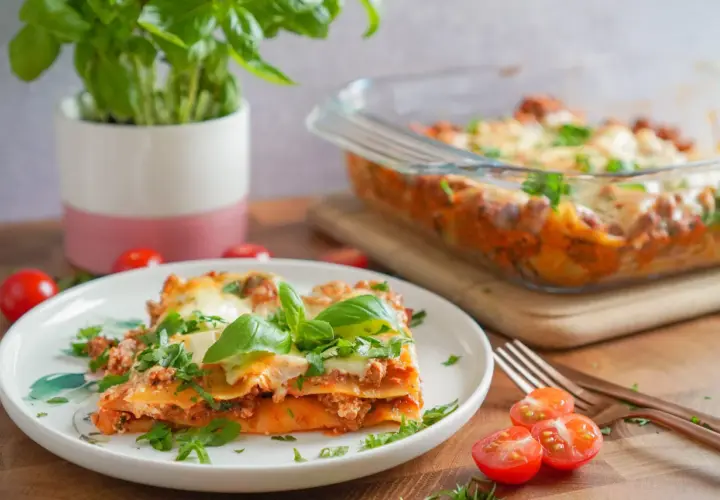 Pyszna lasagne na talerzu, z bazylią i pomidorkami. Idealnie, gdy zastanawiasz się, co podać do lasagne.