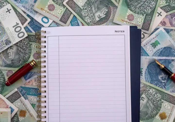 Notatnik i długopis na stosie polskich banknotów. Czy to miejsce na zapisanie, ile zarabia przewodniczący rady miasta?