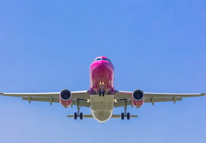 Różowy samolot Wizzair z wysuniętym podwoziem, gotowy do lądowania. Tak wygląda odprawa online Wizzair - szybko i sprawnie!