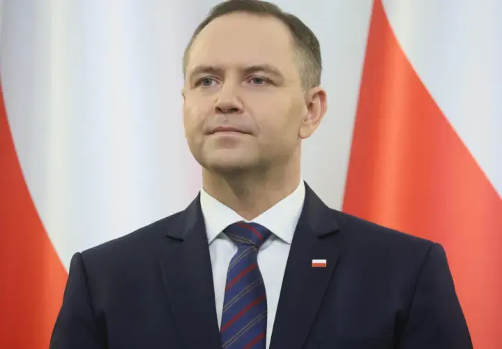 Mężczyzna w garniturze przed polską flagą. Czy to symbol ukrytych kosztów utrzymania Kancelarii Prezydenta RP w ostatnim roku kadencji?