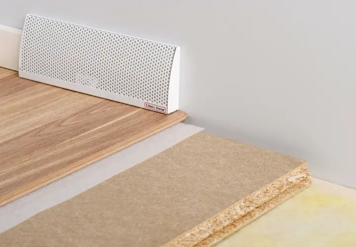 En vit ventilationsgaller för ett passivt ventilerat golv, med trägolv och byggmaterial.