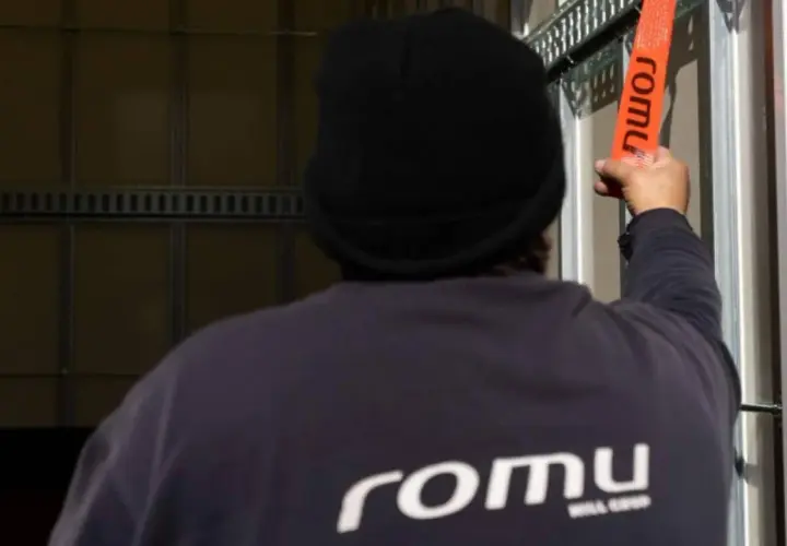 Persona con gorro negro asegura trincajes de cargas con una cinta naranja de la marca Romu.