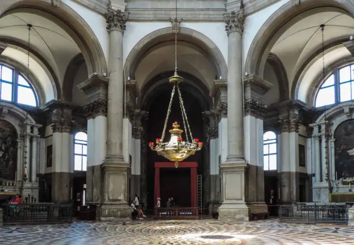 Intérieur de la basilique Santa Maria della Salute, avec son lustre imposant, ses colonnes majestueuses et son sol orné.