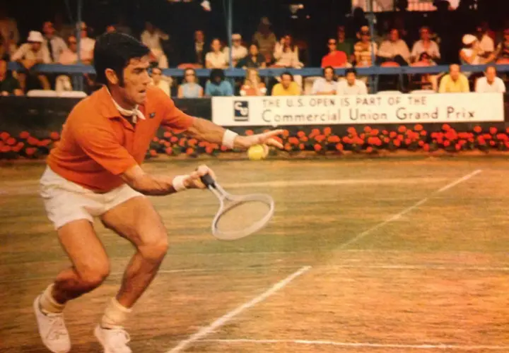 Ken Rosewall w akcji na korcie, w pomarańczowej koszulce i białych spodenkach, podczas meczu U.S. Open.