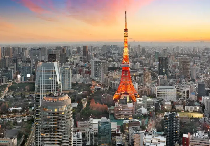 Wieżowiec Tokyo Tower oświetlony na czerwono na tle rozległego, największego miasta na świecie, Tokio, podczas zachodu słońca.