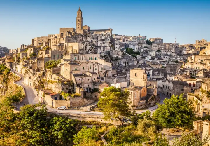 A panoramic view of Matera, Italy, showcasing its ancient cave dwellings and stone buildings cascading down a hillside, resembling a natural map.