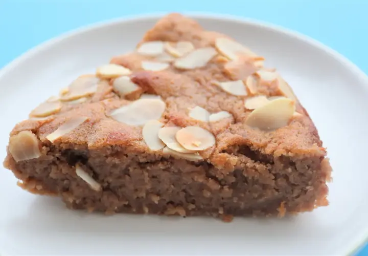 Tranche de gâteau à la crème de marron, garnie d'amandes effilées, sur une assiette blanche.