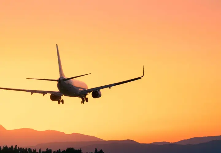 Flugzeug im Landeanflug bei Sonnenuntergang. Man fragt sich, wie viel eher am Flughafen sein, um diesen Anblick zu genießen.
