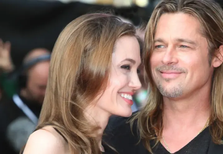 Angelina Jolie i jej mąż Brad Pitt uśmiechają się do siebie na czerwonym dywanie.