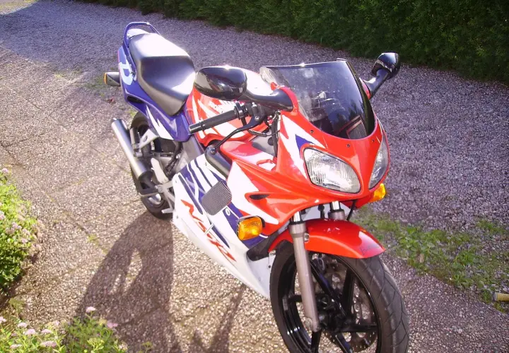 Sportowy motocykl Honda NSR 125 w czerwono-biało-niebieskich barwach, idealny do poznawania jego danych technicznych.