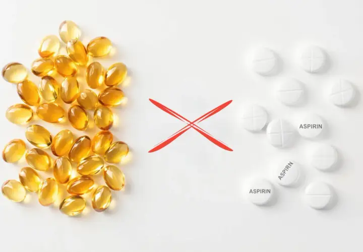 Kapsułki z omega-3 i tabletki z aspiryną, rozdzielone czerwonym krzyżykiem. Unikaj łączenia omega-3 z aspiryną.
