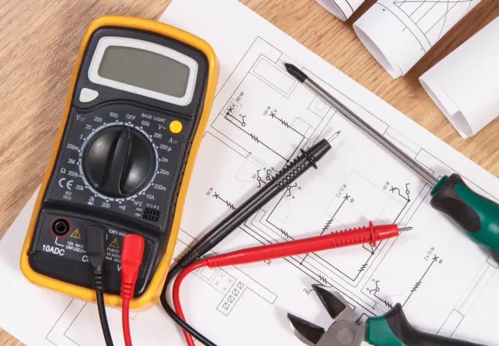 Narzędzia elektryka i schemat instalacji elektrycznej. Multimetr, śrubokręt, kombinerki i przewody gotowe do wykonania oświadczenia elektryka o wykonaniu instalacji elektrycznej.