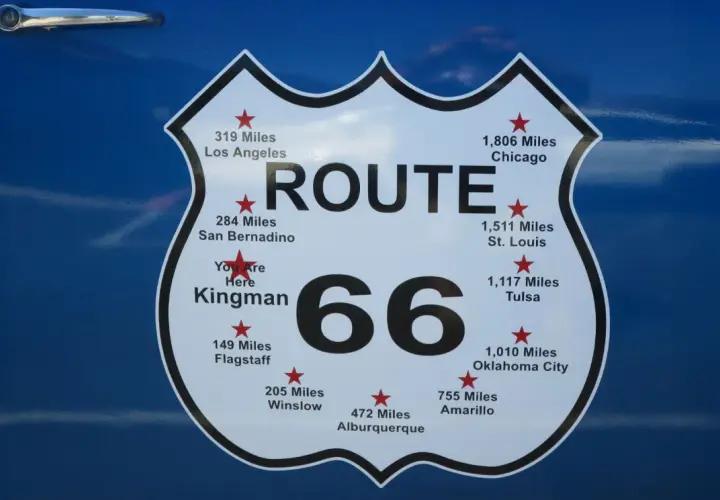 Tablica z napisem "ROUTE 66" i odległościami do miast, np. Chicago, Los Angeles. To symbol legendarnej drogi 66 w USA.