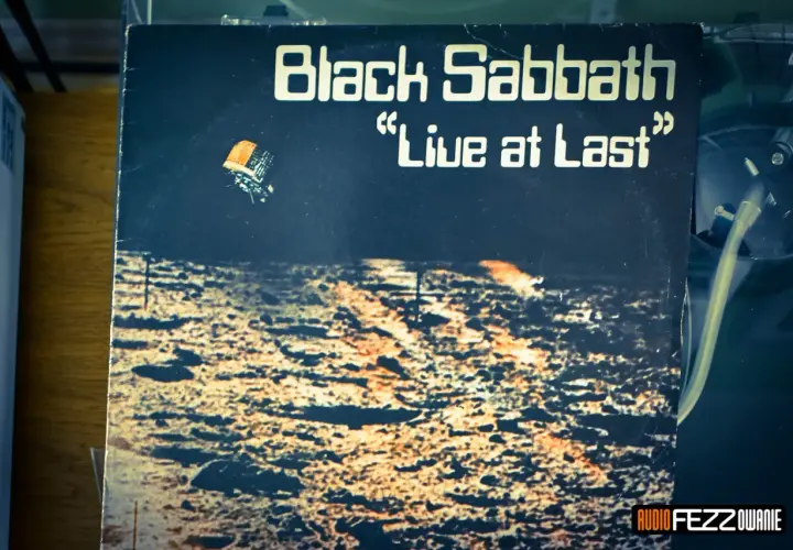 Okładka płyty "Black Sabbath 'Live at Last'". Widok z lotu ptaka na pustynny krajobraz, z małym pojazdem unoszącym się w powietrzu.