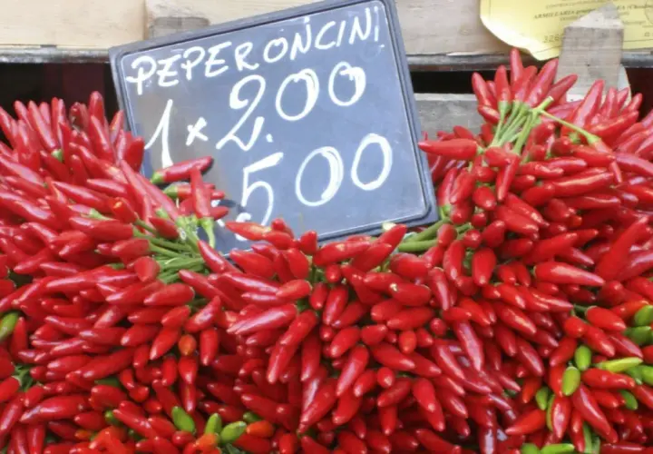 Montón de peperoncini rojos y verdes frescos, con un cartel que indica "Peperoncini 1x2.00 5.00".