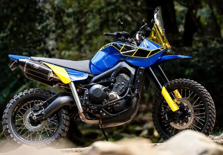 Eine blaue Yamaha Ténéré mit gelben Akzenten und Offroad-Reifen steht im Freien.
