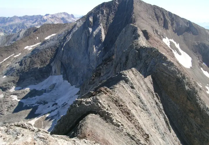 Cresta rocosa y escarpada, con restos de nieve, que se asemeja a un pico espadas en la inmensidad de las montañas.