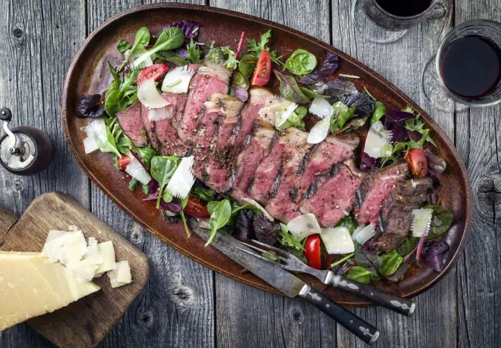 Tagliata succulenta in friggitrice ad aria, servita con insalata mista, scaglie di parmigiano e pomodorini.