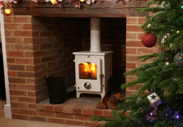 Installation d'un poêle à granulés avec conduit existant dans une cheminée en briques, décorée pour Noël.