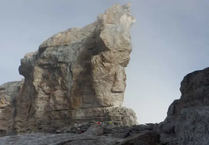 Impresionante vista de la brecha de Rolando, con imponentes formaciones rocosas y un cielo brumoso. Pequeños puntos de color sugieren la presencia de excursionistas.