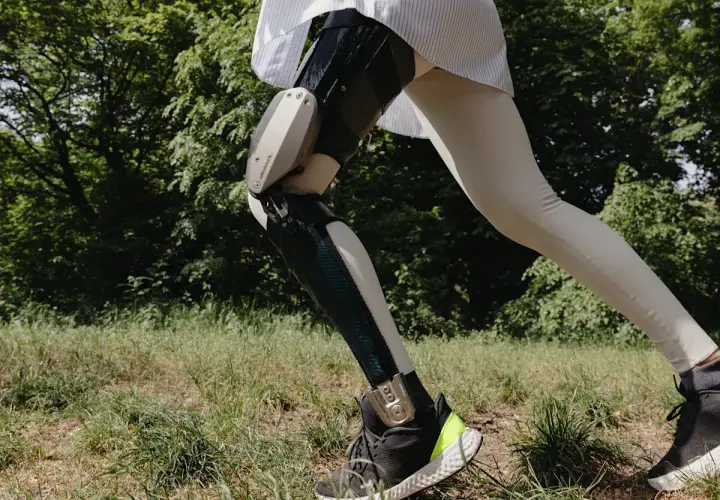 Eine Person mit einer C-Brace Orthese läuft durch grünes Gras.