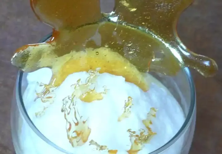 Un verre de crème aérienne surmonté d'une décoration en caramel craquant. Ces oeufs à la neige sont prêts à être dégustés.