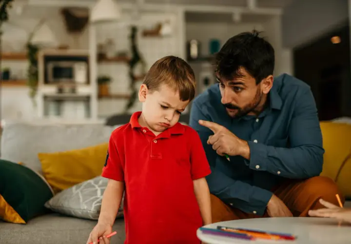 Padre explica a su hijo de 5 años cómo educar con paciencia, mientras el niño muestra una expresión de desánimo.