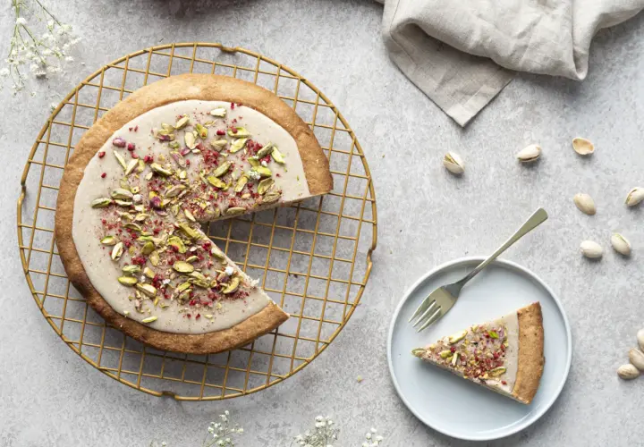 Mazurek stary przepis z pistacjami i malinami, udekorowany na złotej kratce.
