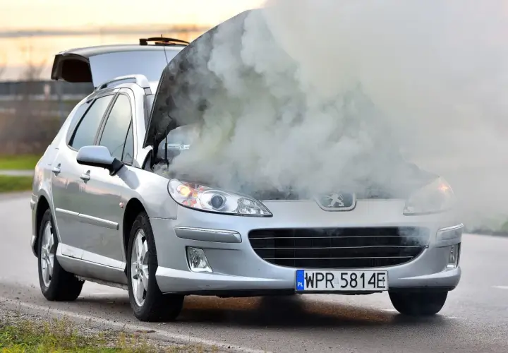 Srebrny Peugeot z otwartą maską, z której bucha dym. Rozbiegany silnik diesla dał o sobie znać w najgorszym momencie.