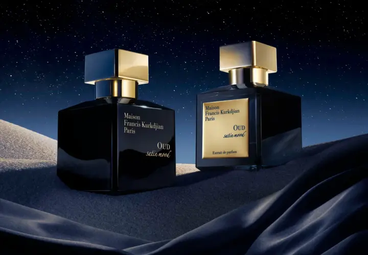 Dwa luksusowe flakony perfum Maison Francis Kurkdjian OUD satin mood na tle nocnego, gwieździstego nieba i piaszczystych wydm.