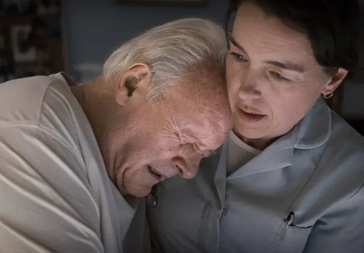 Anthony Hopkins kämpar med demens, hans ansikte uttrycker smärta medan en kvinna tröstar honom.