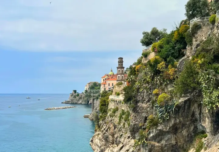 Coastal view of Amalfi with a church tower. Consider a ferry or bus for how to get from Amalfi to Naples.